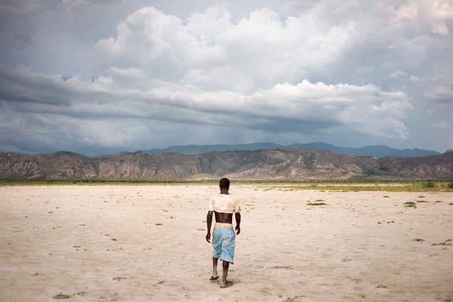 A man walking to his village through Savanne Dèsolèe, considered to be the largest desert area of the country. In the background, one sees deforested mountains.